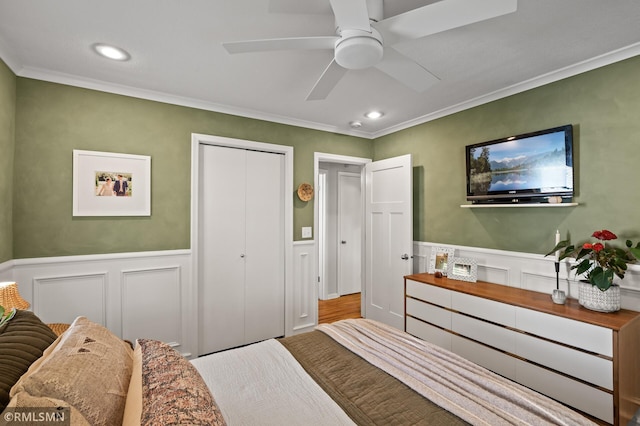 bedroom with wainscoting, ceiling fan, ornamental molding, a closet, and recessed lighting