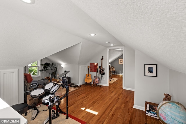 office area with a textured ceiling, vaulted ceiling, wood finished floors, and baseboards