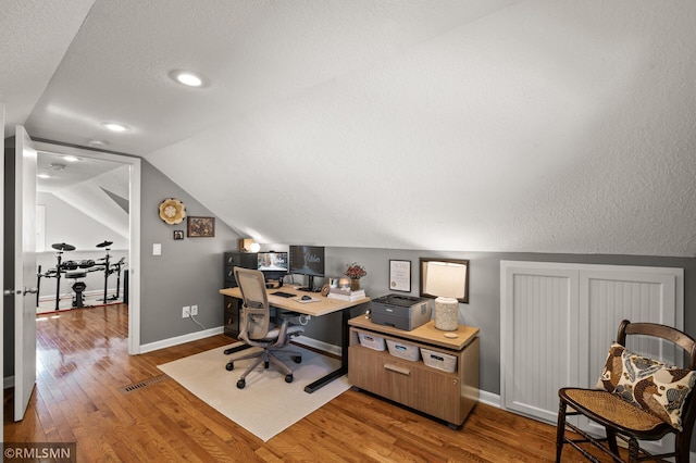 office space featuring vaulted ceiling, baseboards, and light wood-style floors