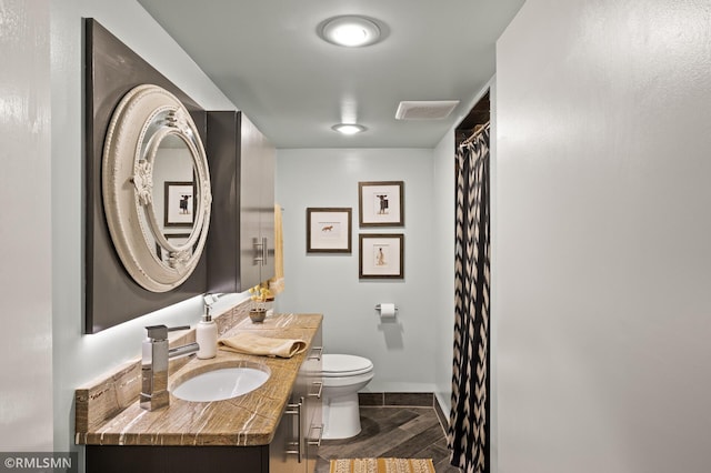 full bath with baseboards, visible vents, toilet, wood finished floors, and vanity