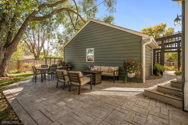 view of patio featuring outdoor dining space, outdoor lounge area, and fence