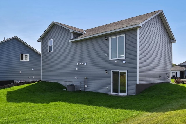 rear view of house featuring central AC and a yard