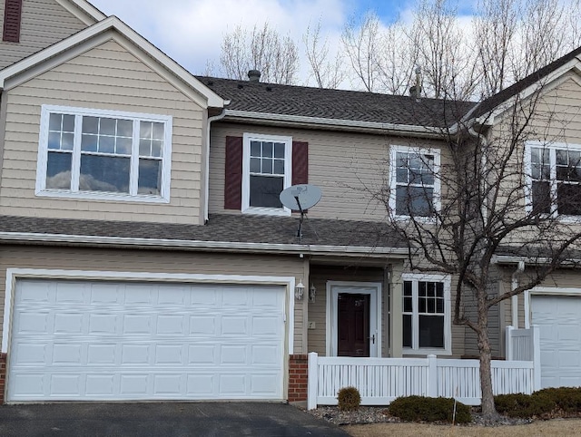 multi unit property with a garage, a shingled roof, and driveway