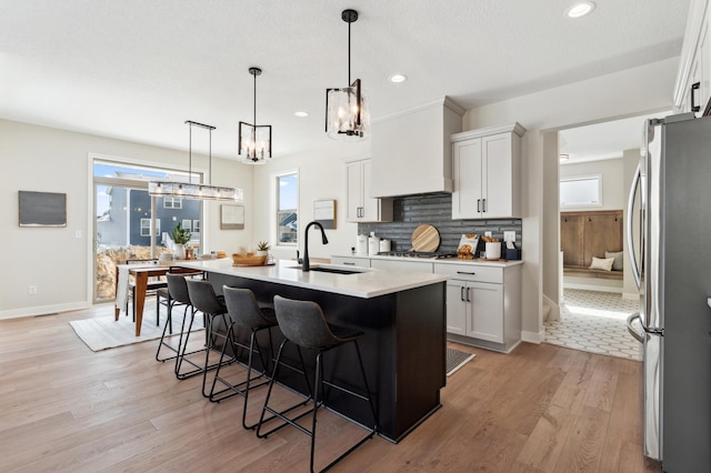 17905 Hidden Creek Trl, Lakeville, MN 55044 - kitchen with stainless steel appliances, a chandelier, a kitchen breakfast bar, light wood-style floors, and white cabinetry