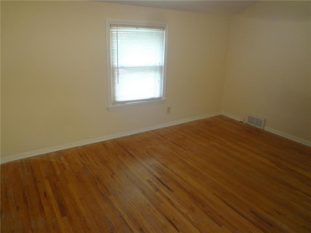 unfurnished room with wood finished floors, visible vents, and baseboards