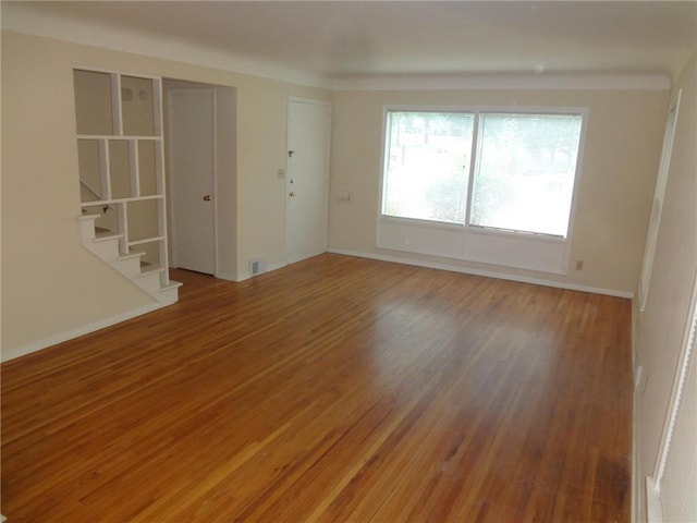 empty room with light wood finished floors, stairway, and baseboards