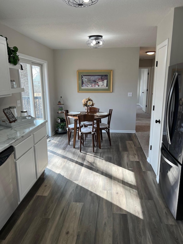 dining room featuring a textured ceiling, baseboards, and dark wood-type flooring