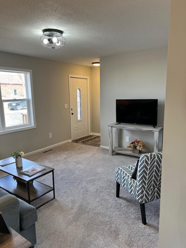 living room with carpet floors, visible vents, a textured ceiling, and baseboards