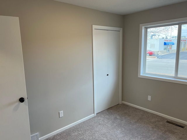 unfurnished bedroom featuring baseboards, visible vents, and carpet flooring