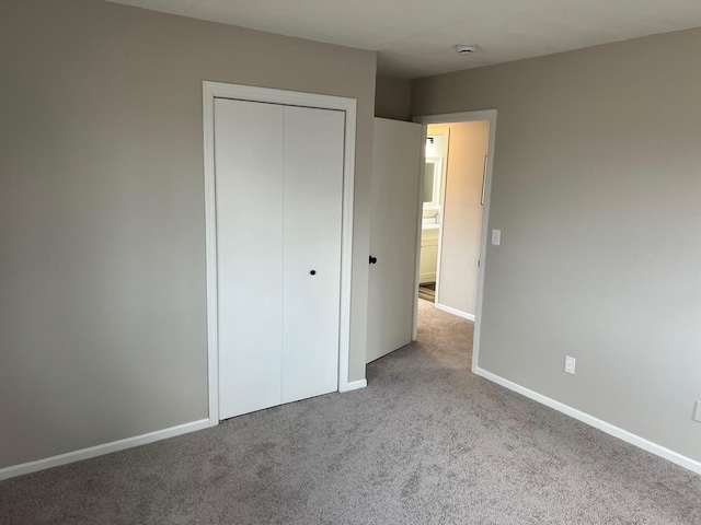 unfurnished bedroom with a closet, carpet flooring, and baseboards