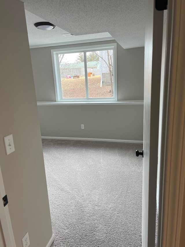 spare room with carpet floors, baseboards, and a textured ceiling