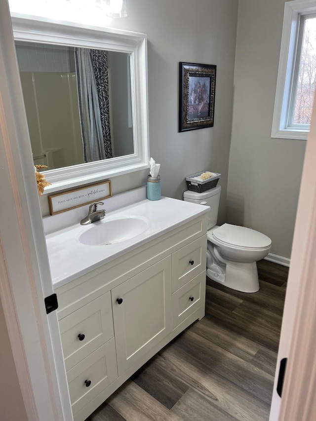 bathroom with baseboards, toilet, wood finished floors, curtained shower, and vanity