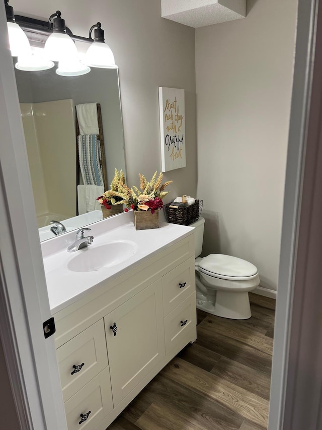 full bath with baseboards, vanity, toilet, and wood finished floors