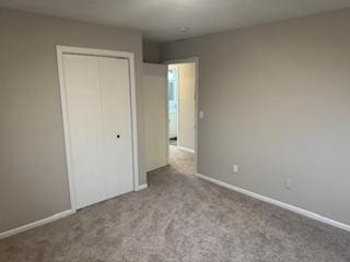 unfurnished bedroom featuring carpet floors, a closet, and baseboards