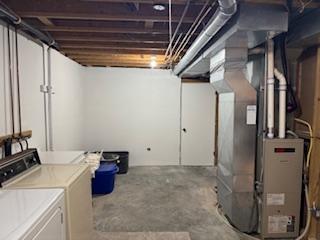 unfinished basement with heating unit and separate washer and dryer