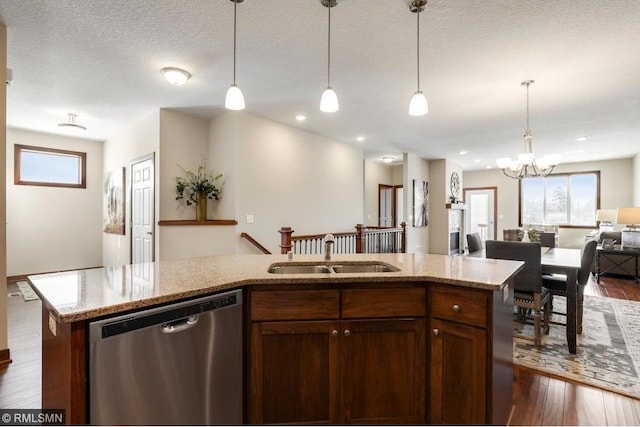 kitchen with light stone counters, dark wood-type flooring, a sink, open floor plan, and stainless steel dishwasher