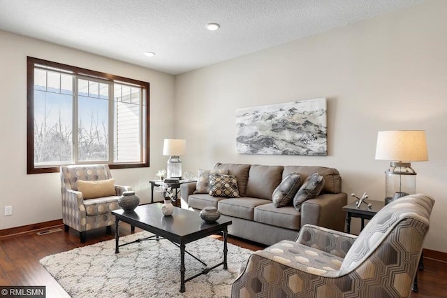 living room featuring dark wood-style floors, visible vents, a textured ceiling, and baseboards