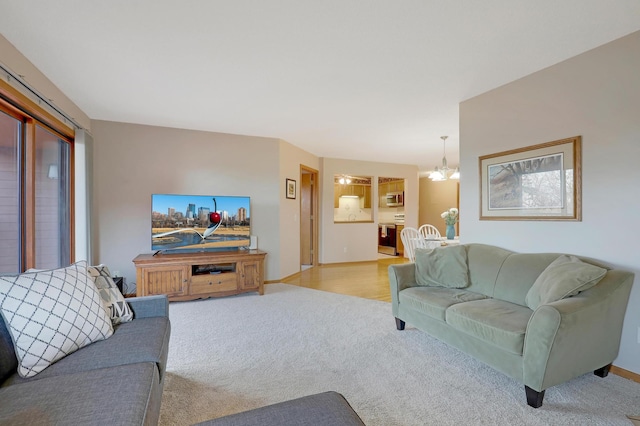 living room with light colored carpet, baseboards, and an inviting chandelier