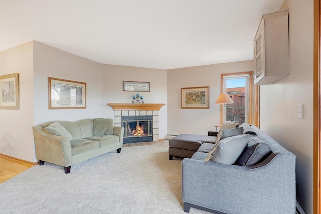 living area featuring light carpet, a baseboard heating unit, and a tile fireplace