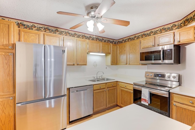 kitchen featuring ceiling fan, a textured ceiling, stainless steel appliances, a sink, and light countertops