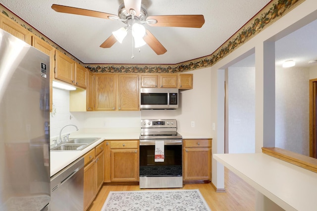 kitchen featuring appliances with stainless steel finishes, light wood-type flooring, light countertops, and a sink