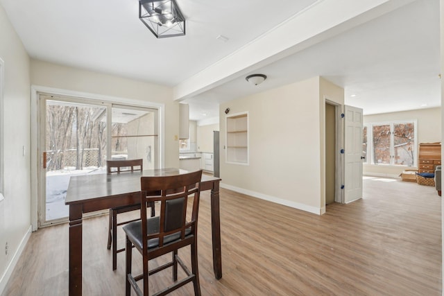 dining area featuring light wood-style flooring and baseboards