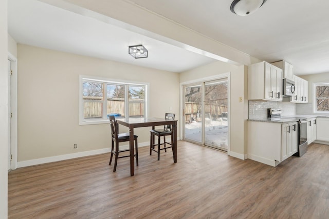 dining space featuring light wood-style flooring and baseboards