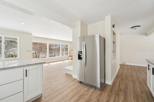 kitchen with baseboards, visible vents, stainless steel fridge with ice dispenser, light stone countertops, and light wood-style floors