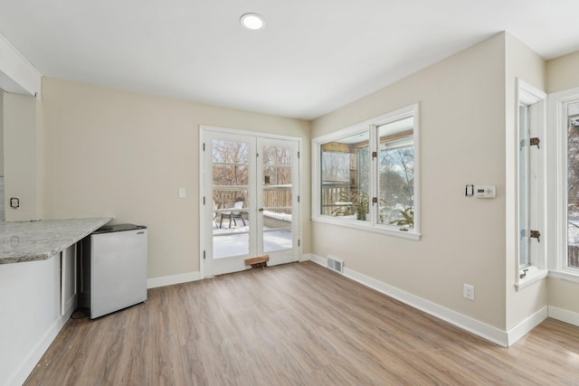 unfurnished dining area with light wood-style flooring, visible vents, and baseboards