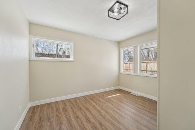 spare room featuring visible vents, baseboards, and wood finished floors