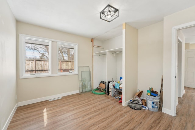 unfurnished bedroom featuring a closet, wood finished floors, visible vents, and baseboards