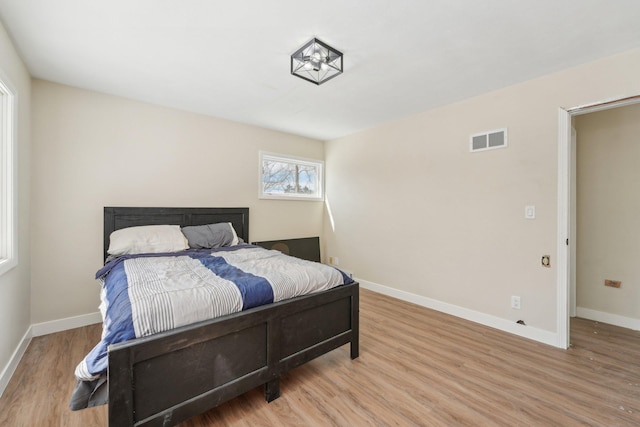 bedroom with wood finished floors, visible vents, and baseboards