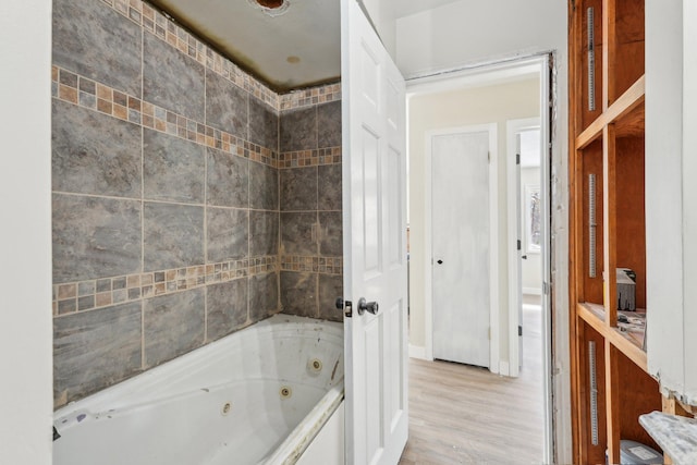 full bathroom with a jetted tub and wood finished floors