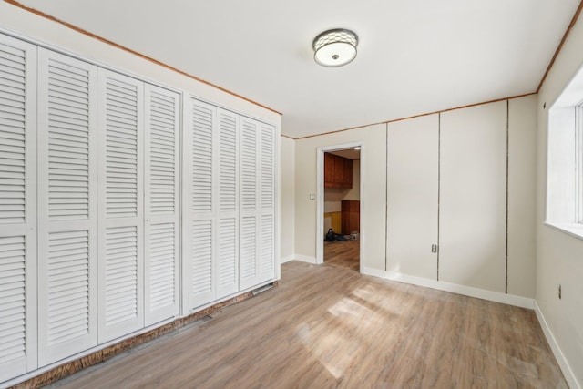 unfurnished bedroom featuring a closet, baseboards, and wood finished floors