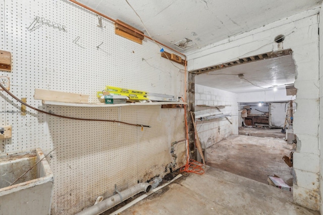 miscellaneous room featuring concrete block wall, concrete floors, and a workshop area