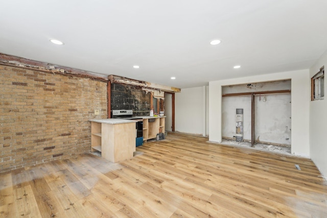 kitchen with light wood finished floors, brick wall, light countertops, stainless steel range with electric cooktop, and open shelves