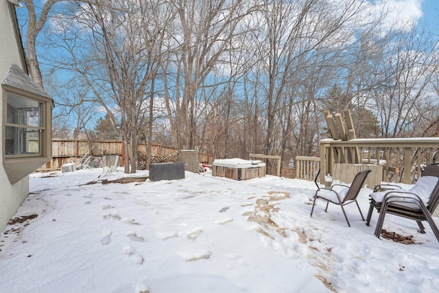 yard covered in snow featuring a hot tub, fence, and a deck