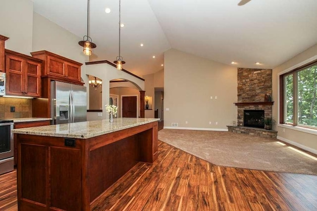 kitchen with a stone fireplace, dark wood-style flooring, a kitchen island, open floor plan, and stainless steel fridge with ice dispenser