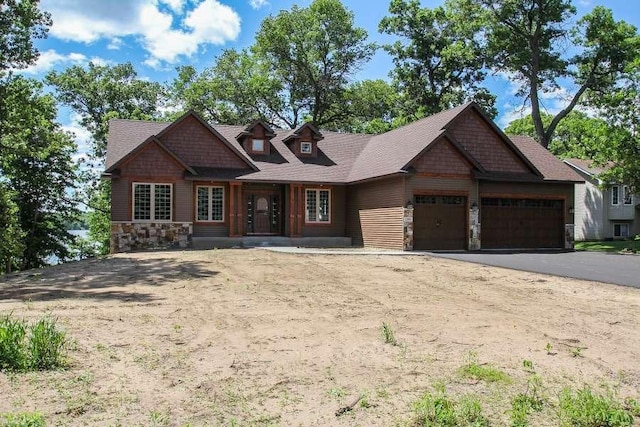 craftsman-style home with stone siding, driveway, and an attached garage