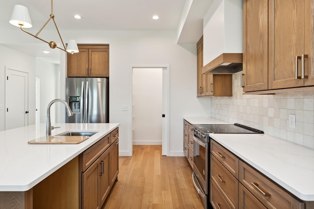 kitchen with premium range hood, decorative backsplash, a sink, appliances with stainless steel finishes, and brown cabinets