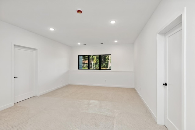 empty room with baseboards, recessed lighting, and light carpet