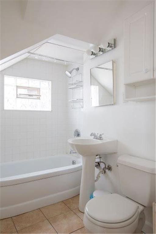 full bath featuring washtub / shower combination, tile patterned flooring, and toilet