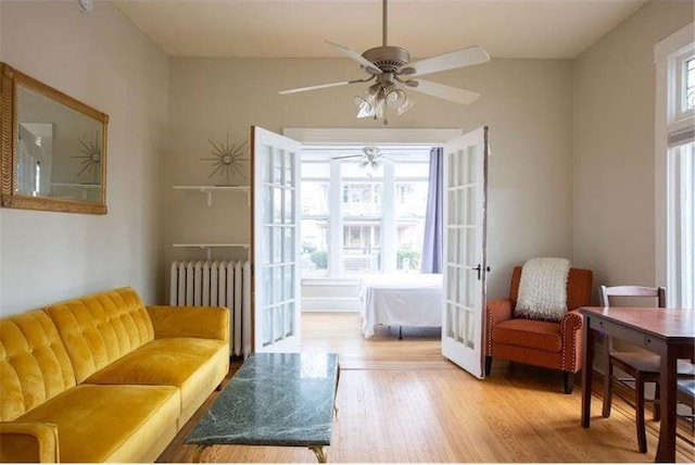 sitting room featuring ceiling fan, wood finished floors, a wealth of natural light, and radiator