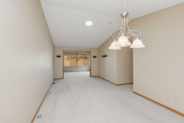 spare room featuring lofted ceiling, light colored carpet, and baseboards