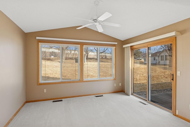 carpeted spare room featuring lofted ceiling, visible vents, and baseboards