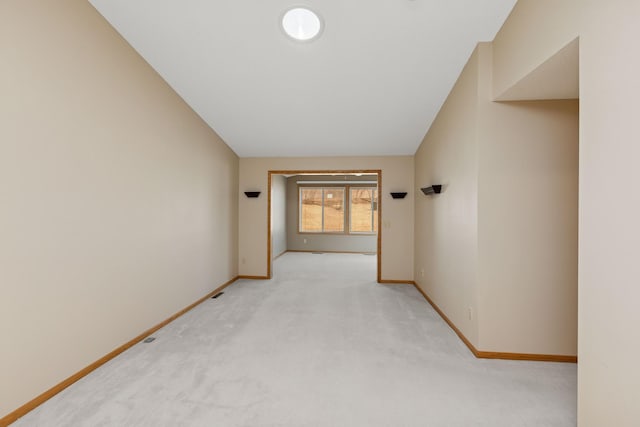 spare room with baseboards, lofted ceiling, and light colored carpet