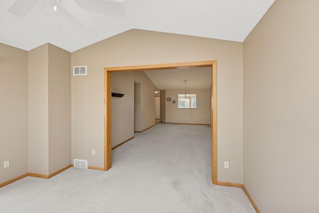 carpeted spare room featuring lofted ceiling, baseboards, and visible vents