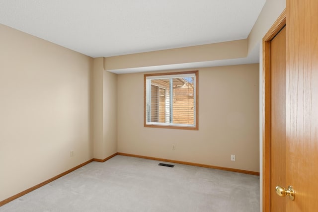 carpeted spare room featuring visible vents and baseboards