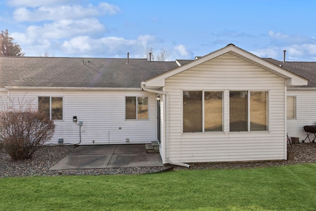 back of property with a patio area, a shingled roof, and a lawn