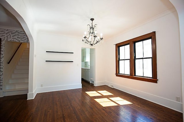 spare room featuring baseboards, arched walkways, dark wood-type flooring, stairs, and crown molding